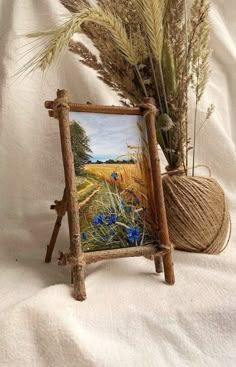 a painting is on display next to a yarn ball and some plants in front of it