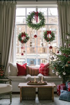 a living room decorated for christmas with wreaths on the windowsill