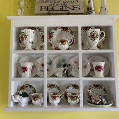 the china cabinet is filled with dishes and cups, which are decorated with floral designs