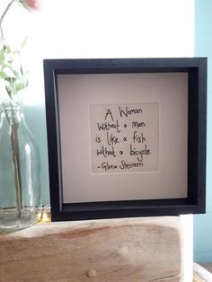 a vase with flowers in it sitting next to a framed piece of paper that says, a human without a man is like a fish when a biggie