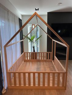 a wooden bed frame with a plant in the middle and a house shaped window above it