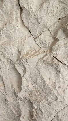 a white rock wall with cracks in it