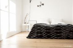 a bed sitting on top of a wooden floor next to a window