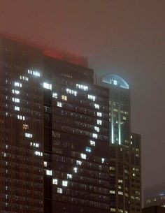 a very tall building with lots of windows in the city at night, lit up by street lights