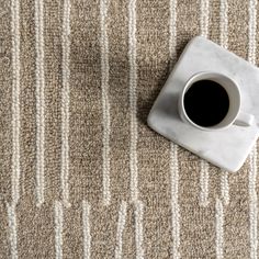 a cup of coffee sitting on top of a white marble coaster next to a rug