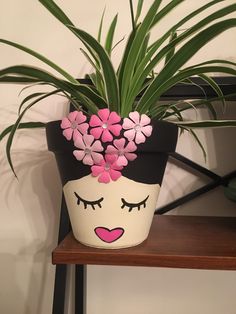 a potted plant with pink flowers in it on a shelf next to a wall