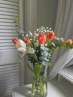 a vase filled with flowers sitting on top of a white table next to a window