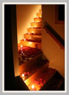 candles are lit on the steps leading up to an indoor area that has been decorated with roses and petals