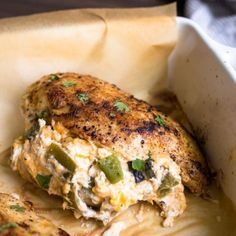 a close up of a chicken dish in a white casserole dish on a wooden table