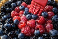 a pie with berries and blueberries in it being held by a red spatula