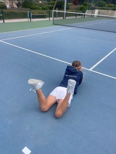 a woman laying on the ground with her tennis racket and water bottle in hand