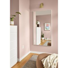 a living room with pink walls and a mirror on the wall above a chair in front of it