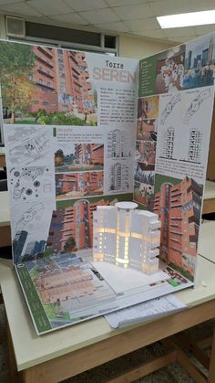 an open brochure with buildings and plans on the table in front of it