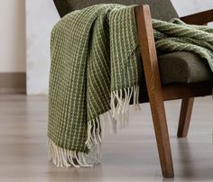 a chair with a green blanket on top of it and a wooden frame around it