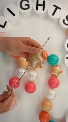 two hands are decorating a birthday cake with candles and candy balls that spell out lights