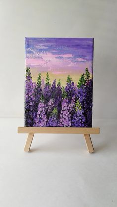 an easel with a painting of purple flowers on it