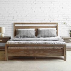 a bed with two nightstands next to it and a brick wall in the background