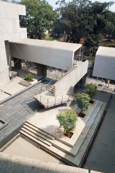 an aerial view of a building with stairs leading up to the top floor and trees in front of it