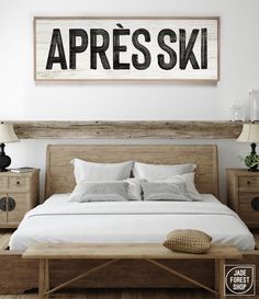 a bed with white sheets and pillows in a bedroom next to a wooden sign that says apres ski