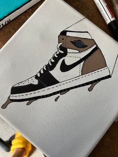 a painting of a shoe on top of a piece of paper next to markers and pens