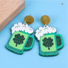 pair of beer and shamrock earrings on blue background