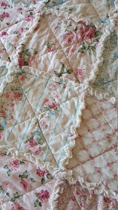 an old fashioned quilt with pink flowers and ruffled edges on it's edge