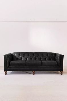 a black leather couch sitting on top of a white floor