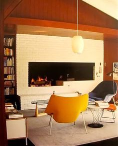 a living room filled with furniture and a fire place next to a book shelf on top of a hard wood floor