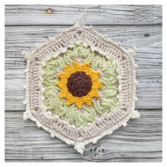 a crocheted sunflower hanging on a wooden wall