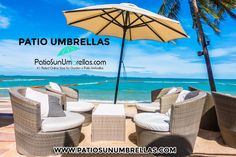 two wicker chairs and an umbrella on the beach with blue water in the background