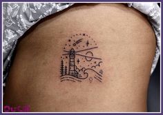 a small lighthouse tattoo on the back of a woman's left thigh, with stars and clouds above it