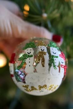 an ornament with snowmen on it being held by someone's hand