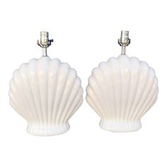 two white shell shaped lamps are shown against a white background