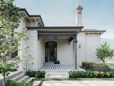 a white house with black and white checkerboard flooring in the front yard