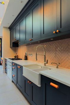 a kitchen with blue cabinets and white counter tops, an orange light on the faucet