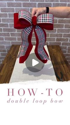 someone is holding up a red bow on top of a wooden table with the words how to double loop bows