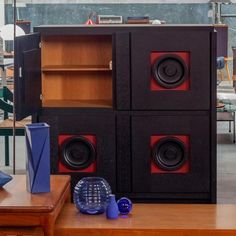 there are speakers that are on the side of this cabinet and in front of it is a blue vase