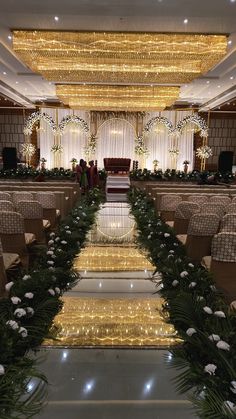 the aisle is decorated with white flowers and greenery as well as lights on the ceiling