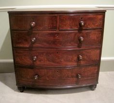 a wooden dresser with several drawers and knobs on it's top shelf in a room