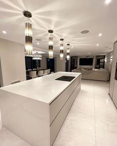 a large kitchen with white counter tops and lights