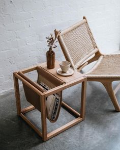 two chairs and a table in front of a brick wall with a vase on it