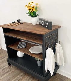 a black and white kitchen cart with some plates on it next to a potted plant