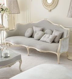 a white couch sitting in a living room next to a mirror