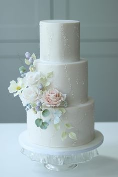 a three tiered white wedding cake with flowers on it