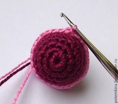 a crocheted ball of yarn next to a pair of knitting needles on a white surface