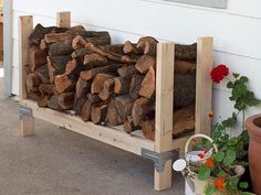 a stack of logs sitting on top of a wooden shelf next to potted plants