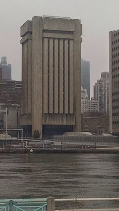 a large building sitting on the side of a river next to tall buildings with lots of windows