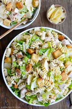 two white bowls filled with pasta salad next to wooden utensils on a table