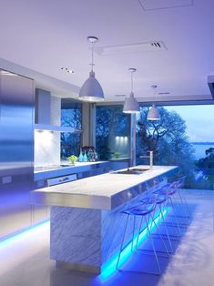 a modern kitchen with an island counter and bar stools in front of the window