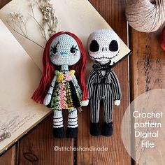 two crocheted dolls sitting next to each other on a wooden table with yarn